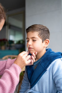 Mother doing an antigen test to her son at home