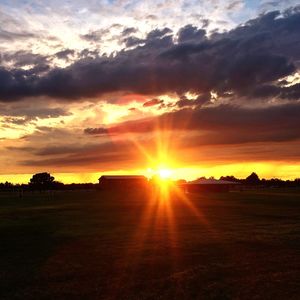 Scenic view of silhouette field against orange sky