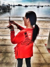 Young woman standing by sea against sky