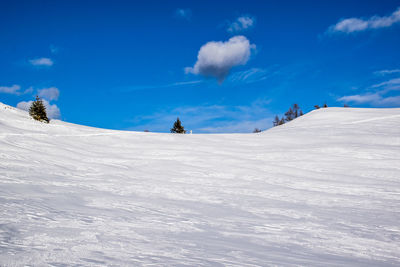 Snow covered land against blue sky