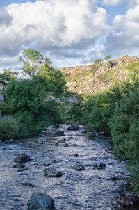 Scenic view of river against cloudy sky