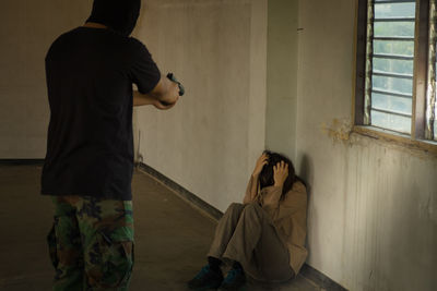 Rear view of man and woman standing against wall