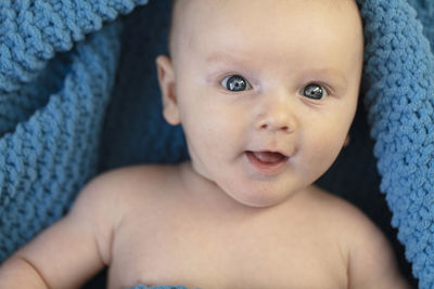 Portrait of cute baby girl lying on bed at home