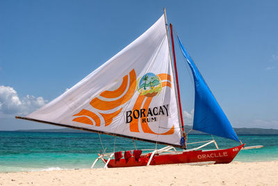 Sailboat on beach against blue sky