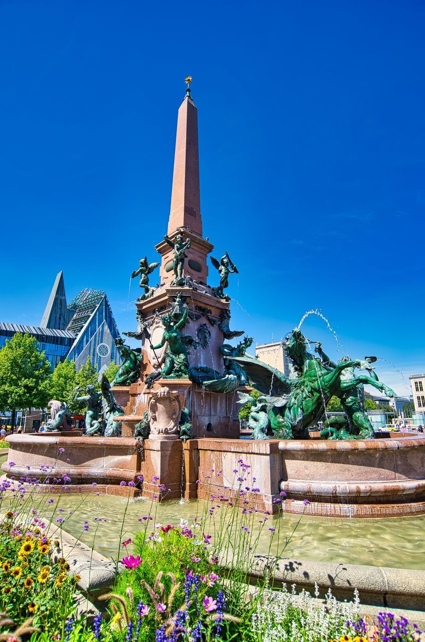 VIEW OF SCULPTURE AGAINST BLUE SKY AND BUILDING