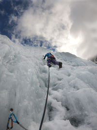 Low angle view of woman ice climbing against sky