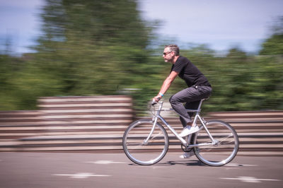 Side view of young man riding bicycle