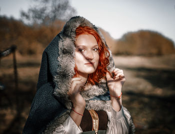 Portrait of young woman wearing fur coat standing outdoors