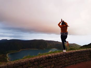 Rear view of man standing on mountain against sky