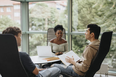 Multiracial students discussing while studying together in university