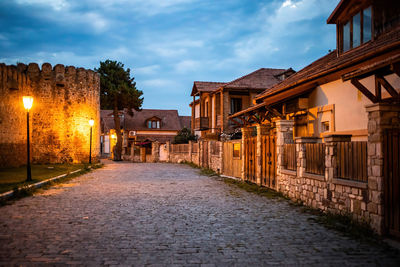 Street amidst buildings against sky at dusk