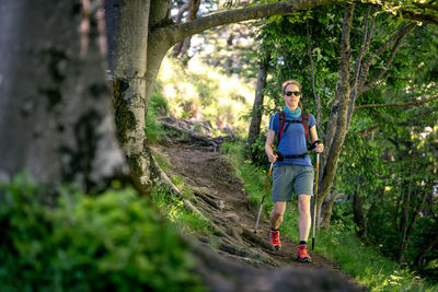 Woman wearing sunglasses hiking in forest