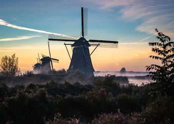 Traditional windmill against sky at sunset