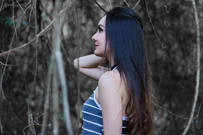 Side view of young woman standing in forest