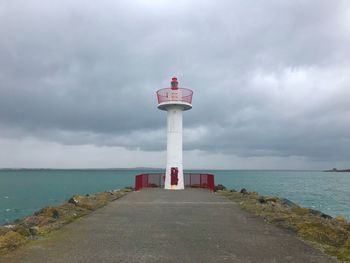 Lighthouse by sea against sky