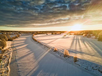 Panoramic view of snow covered land against sky during sunset