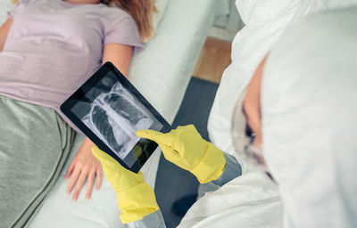 Doctor in protective suit examining x-ray of patient on tablet