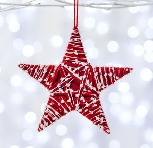 Close-up of woolen star decoration hanging against illuminated light