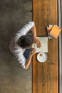 High angle view of man holding coffee cup on table