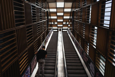 Rear view of man standing on escalator in building
