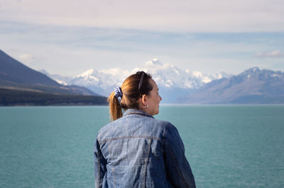 Rear view of woman looking at sea against mountains