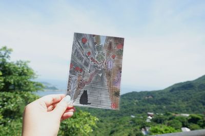Person holding umbrella against sky
