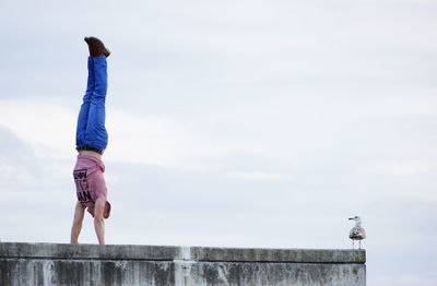 Full length of man doing handstand against sky