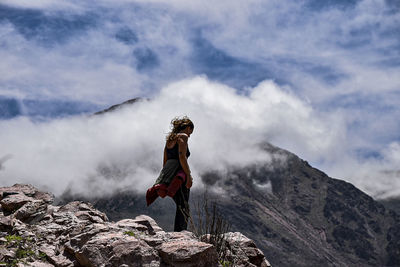 Man standing on rock against sky