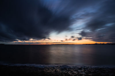 Scenic view of sea against dramatic sky during sunset