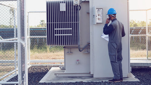 Male engineer talking on mobile phone while checking meter