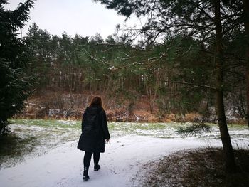 Rear view of woman walking on footpath during winter