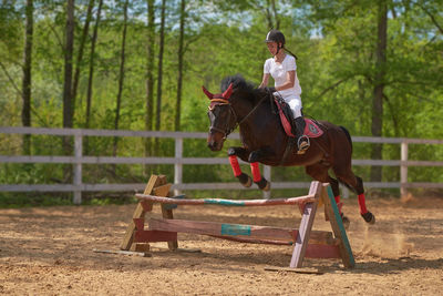 Full length of woman riding horse in ranch