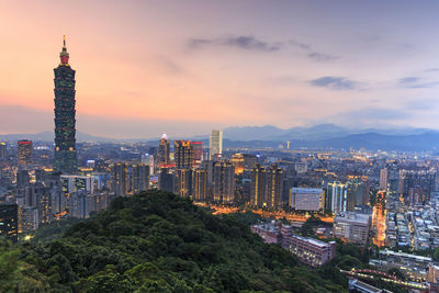 Illuminated cityscape against sky at dusk