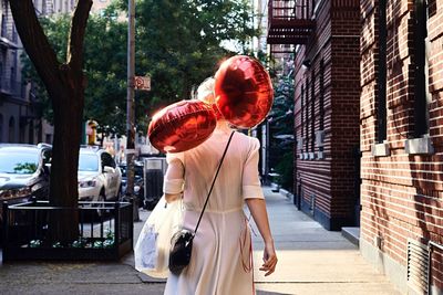 Woman with red balloons  standing in city