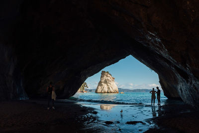 Silhouette couple standing on shore seen through cave