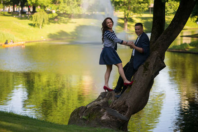 Portrait of couple standing on tree by lake at garden