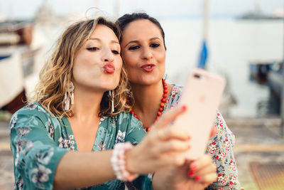 Woman with friend taking selfie from mobile phone