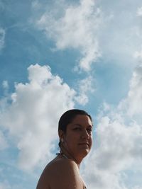 Low angle portrait of mid adult woman against sky