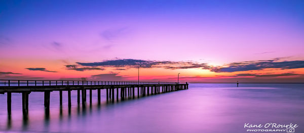 Pier over sea against sky during sunset