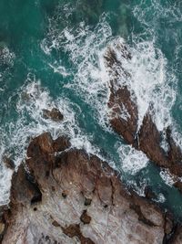 High angle view of waves splashing on rocks