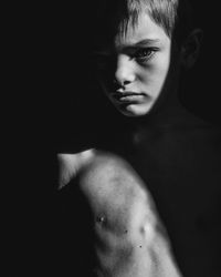 Portrait of shirtless boy standing in dark