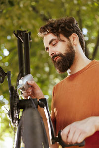 Side view of man using mobile phone while standing outdoors