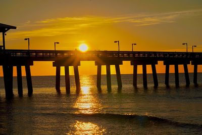 Silhouette pier over sea against sky during sunset