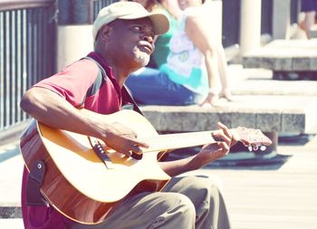 Street musician playing guitar on sunny day