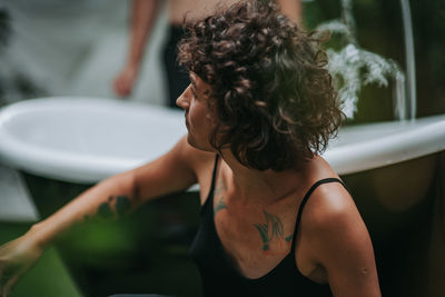 Rear view of shirtless woman sitting in bathroom