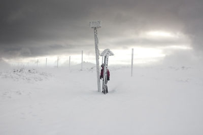 People on snow covered field against sky