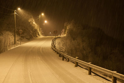 Illuminated snow covered road at night