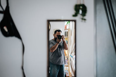 Reflection of man photographing from camera reflecting on mirror