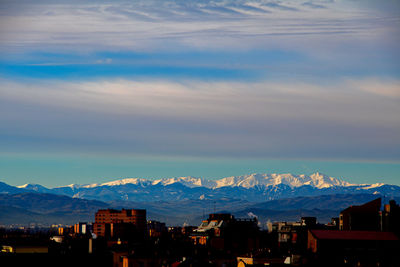 Aerial view of townscape and mountains against sky
