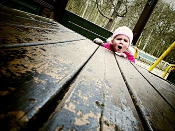 Full length of woman sitting on wooden wall